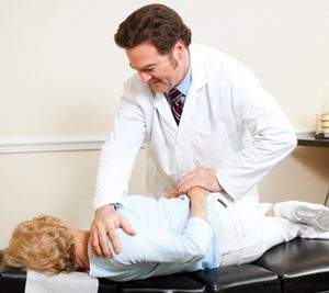 Chiropractor gently adjusting a senior woman's spine.