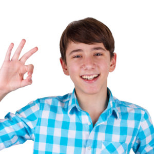 Happy teenager gesturing OK sign and smiling isolated on white background